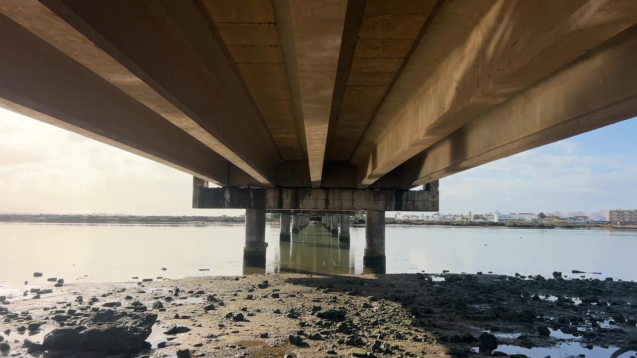 Toma bajo un puente con canal de agua en un día soleado.