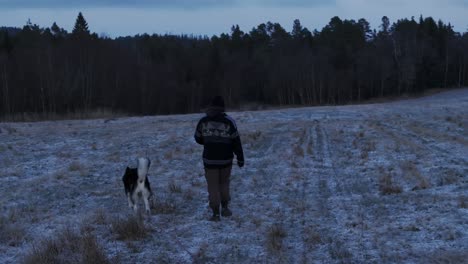 Indre-Fosen,-Kreis-Trondelag,-Norwegen-–-Ein-Mann-Spaziert-Mit-Seinem-Hund-Auf-Dem-Bauernhof-–-Kamerafahrt