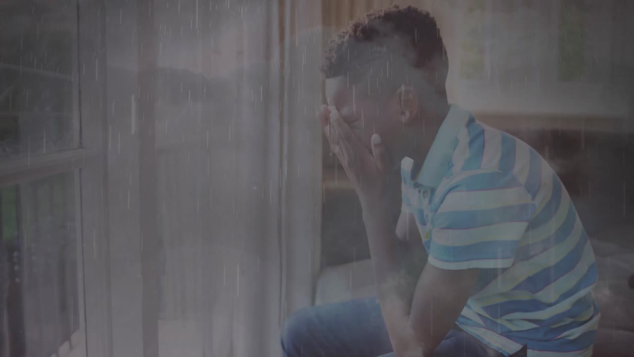 Animation of rain over sad african american boy