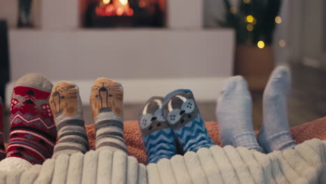 navidad, calcetines y dedos de los pies de la familia junto a la chimenea