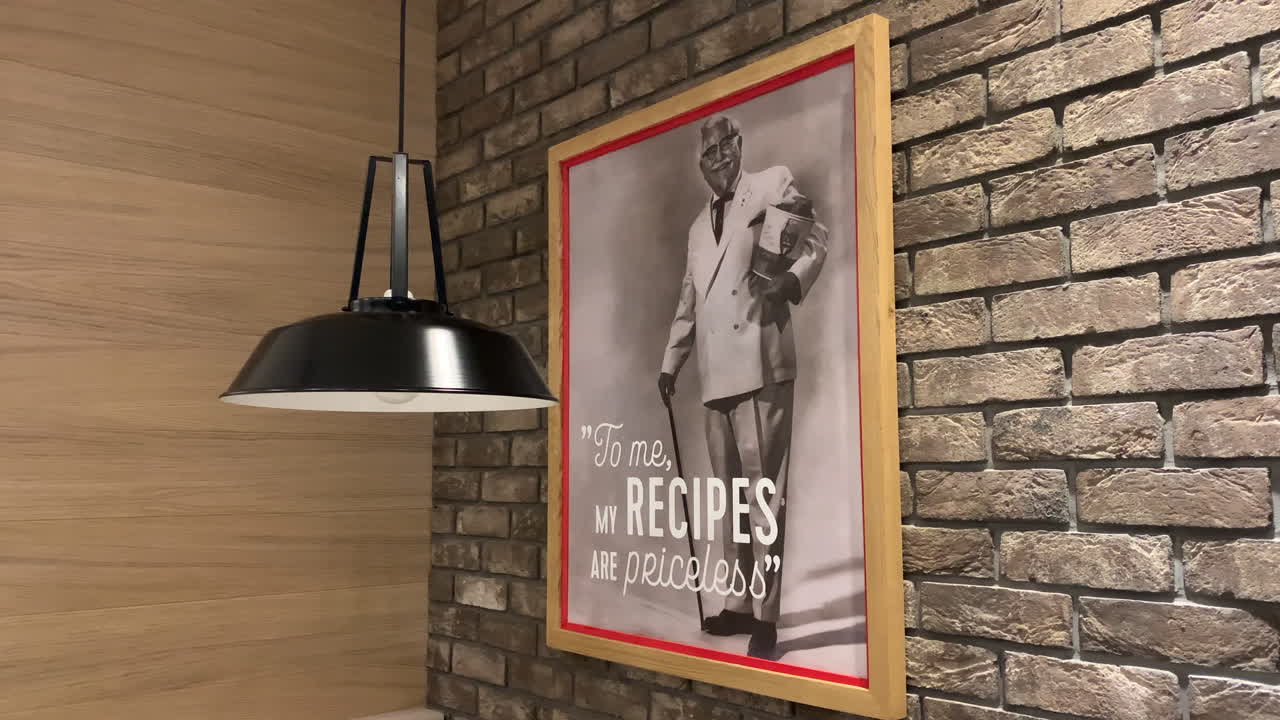 Framed photograph of the KFC owner hanging on the wall. Colonel Sanders pictures on the brick wall. To me, my recipes are priceless. Framed black and white photography.