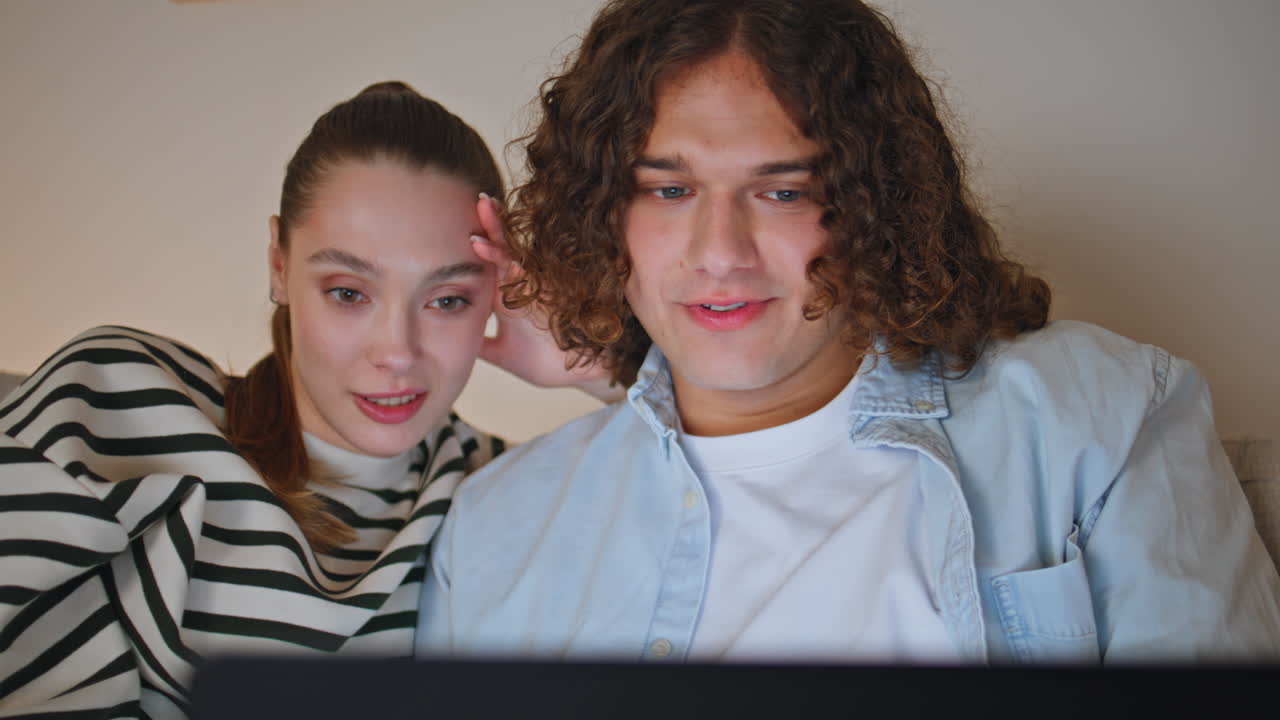 Spouses watching social media content laptop sitting evening apartment closeup