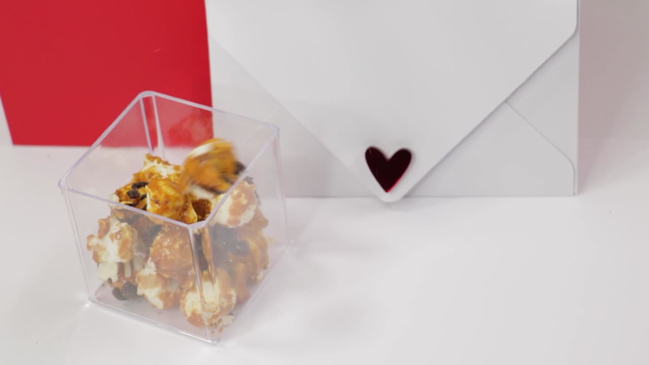 Romantic letter with a heart and caramel popcorn falling into transparent container