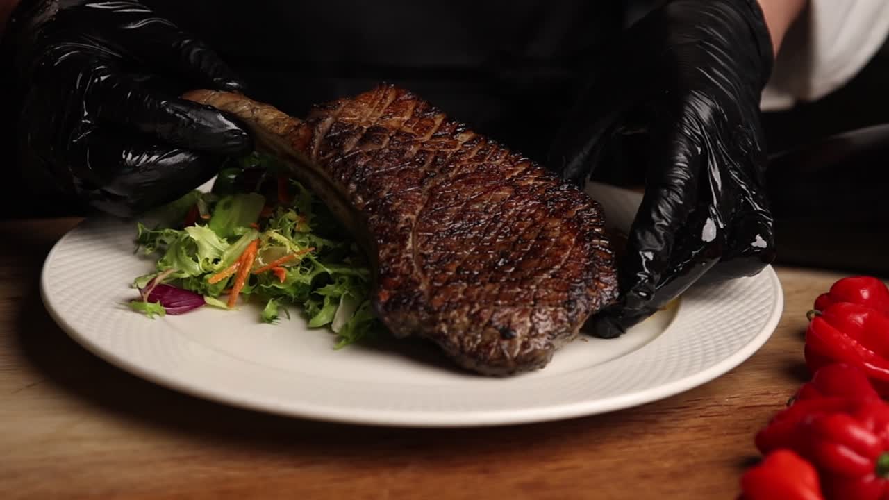 Chef che serve bistecca Tomahawk grigliata con insalata e patate