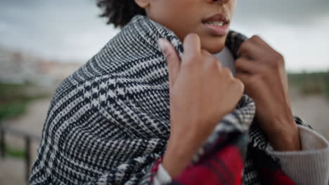 closeup woman chest walking windy beach. african american hands adjusting scarf