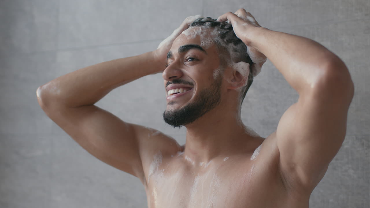 Uomo che si lava i capelli sotto la doccia