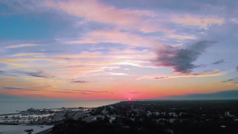 Aerial-shot-of-the-sun-setting-over-a-small-beach-town