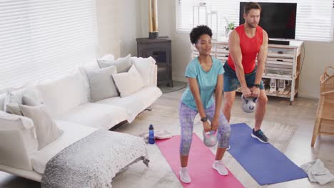 video of happy diverse couple training together at home with weights