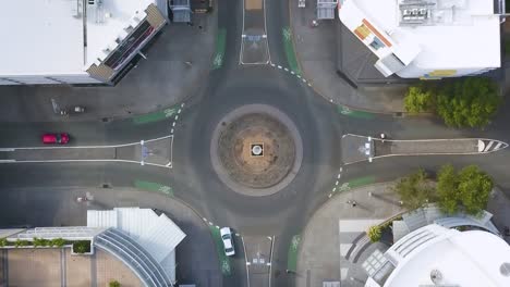 aerial descend on centered roundabout in brisbane as cars enter and exit