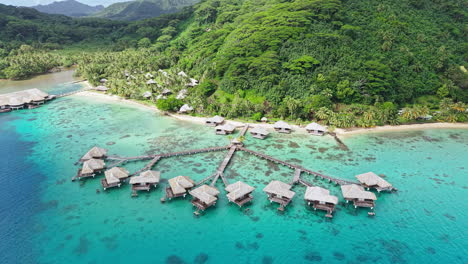 huahine island, french polynesia. drone shot of overwater bungalows in lagoon and green coastal landscape