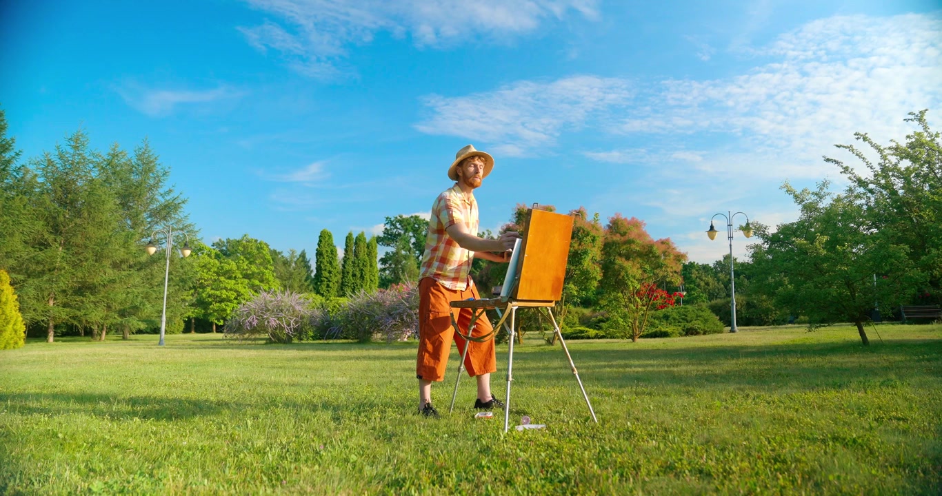 Artista che dipinge all'aperto su un cavalletto in un parco soleggiato