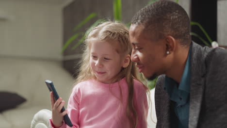little girl shows videos via smartphone to cheerful teacher