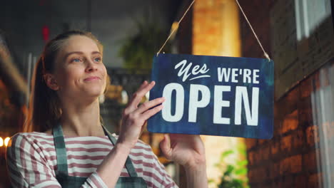 store employee displays closed/open sign