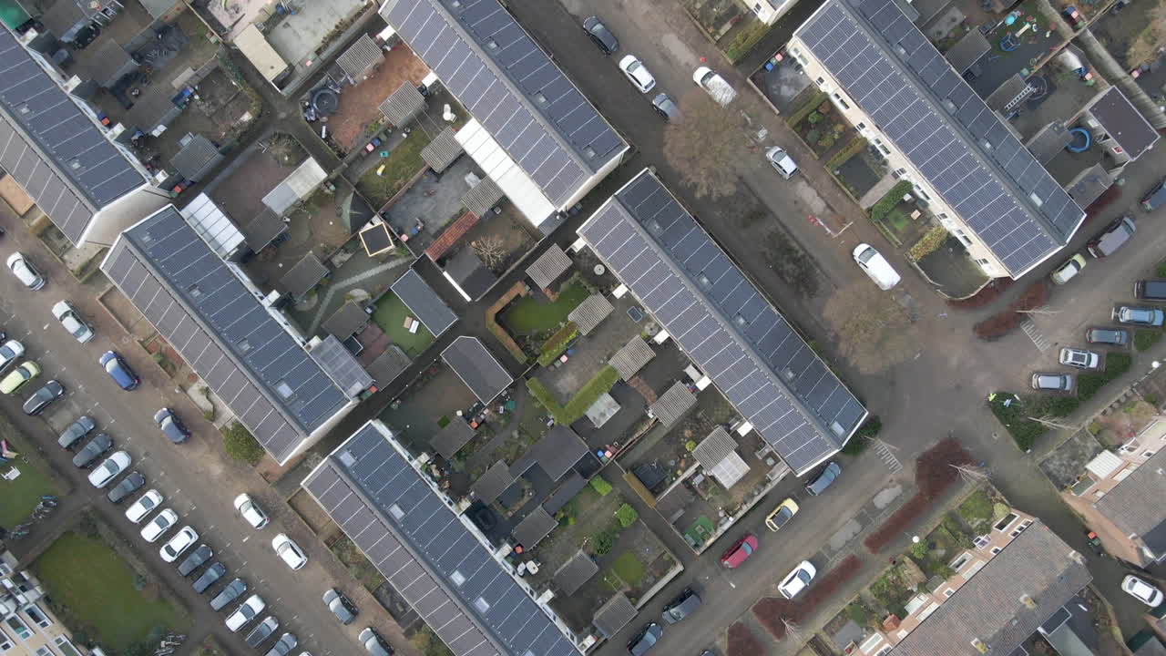 Top down aerial across residential neighbourhood with solar panels on rooftop