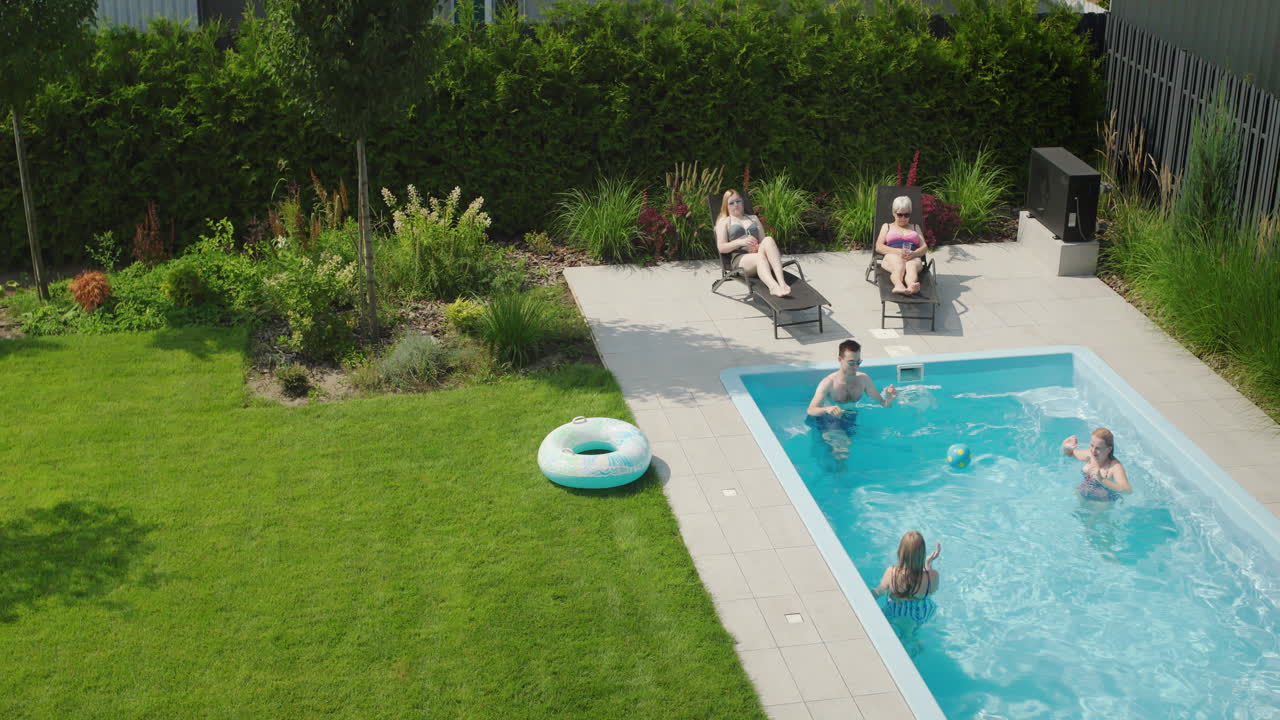 En familie leger med bold i poolen. Hygger sig på en varm sommerdag