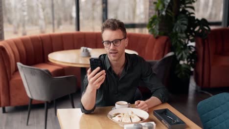 cute young blogger in a cafe shoots a video on a smartphone