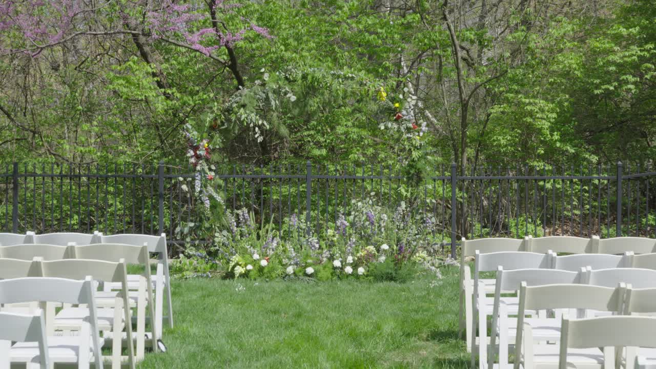 POV (punto di vista) mentre si cammina lungo il corridoio erboso di un luogo per matrimoni all'aperto verso un grande altare ad anello floreale