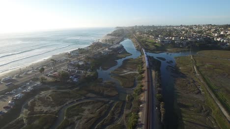 antena alta sobre un tren amtrak que viaja al lado del océano pacífico cerca de san diego 1