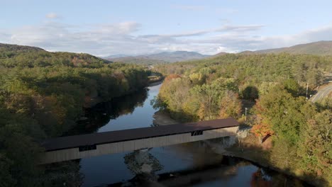 road trip concept - covered bridge in new england river - nature landscape - aerial pullback