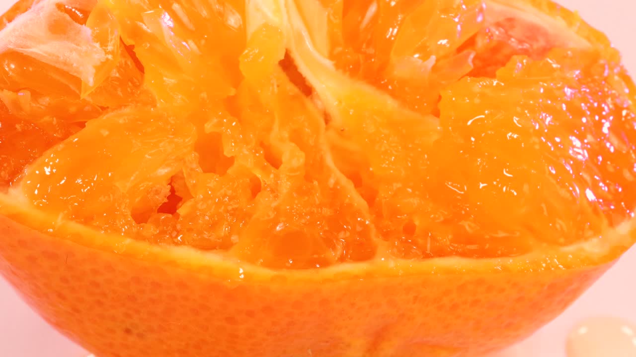 Hand squeezing half tangerine. Fresh liquid explosion, macro shot close up.