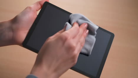 Person Cleaning Tablet Screen with a Cloth