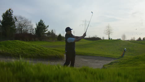 golfer in bunker making great shot on golf course at sunset. low pov, dolly right