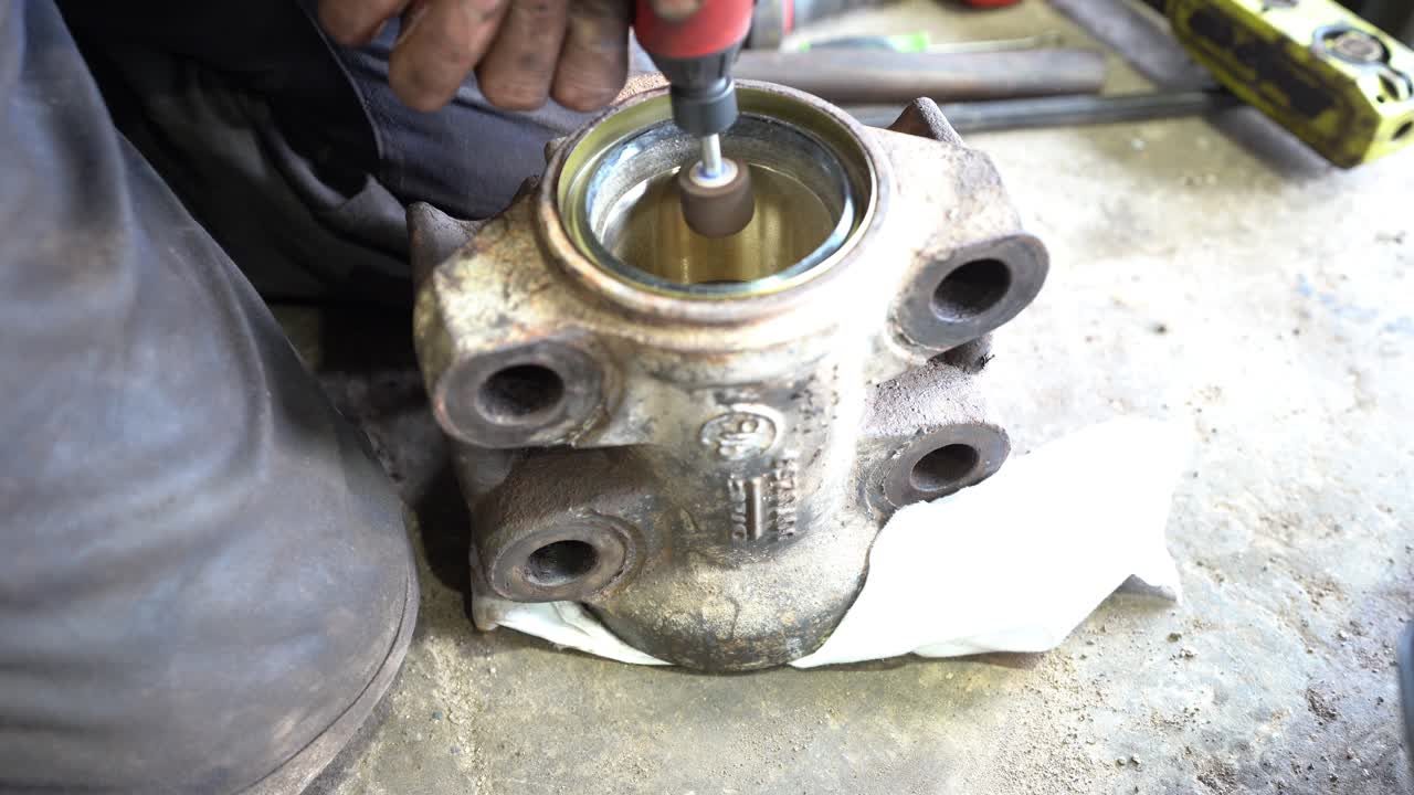 un técnico que limpia los bordes ásperos de una carcasa para un arbusto con un taladro