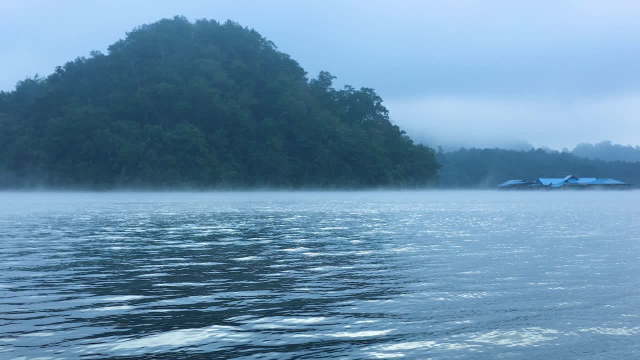 산과 멀리 있는 구조물과 함께 안개가 가득한 강