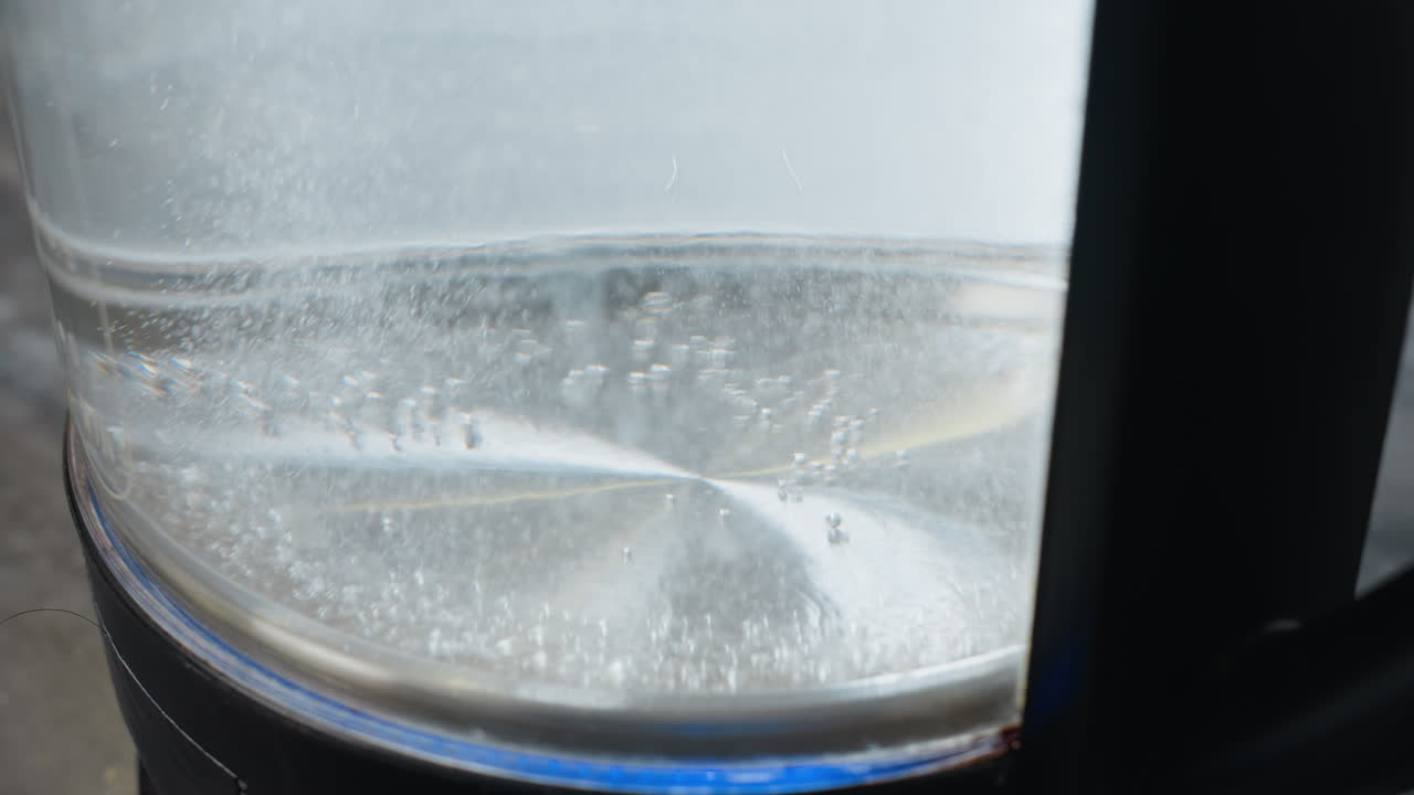 거품이 상승하는 투명한 항아리에 있는 는 물의 클로즈업, 물 보일러에서 가열 과정을 보여주는, 물 수준과 거품이 명확하게 보입니다.