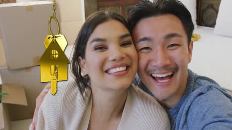 animation of gold house key and key fob over happy diverse couple at new home