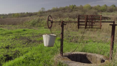 an old water well on rural homestead. an abandoned well in the middle of green grass and trees.