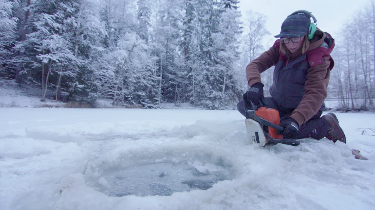휴대용 - 얼음 구멍을 절단하는 전기톱을 사용하는 여성
