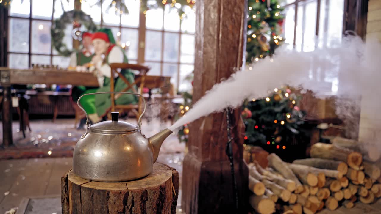 Boiling retro aluminium kettle. Teapot steams. Two elves on the background. New year spirit. Christmas eve. Closeup. Teapot on a log.