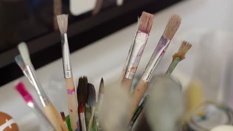 close up pot of small paint brushes in art studio