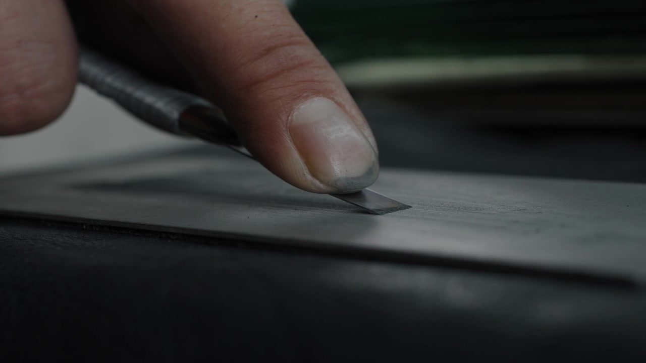 Close-up of hand cutting material with precision knife in shoe production process