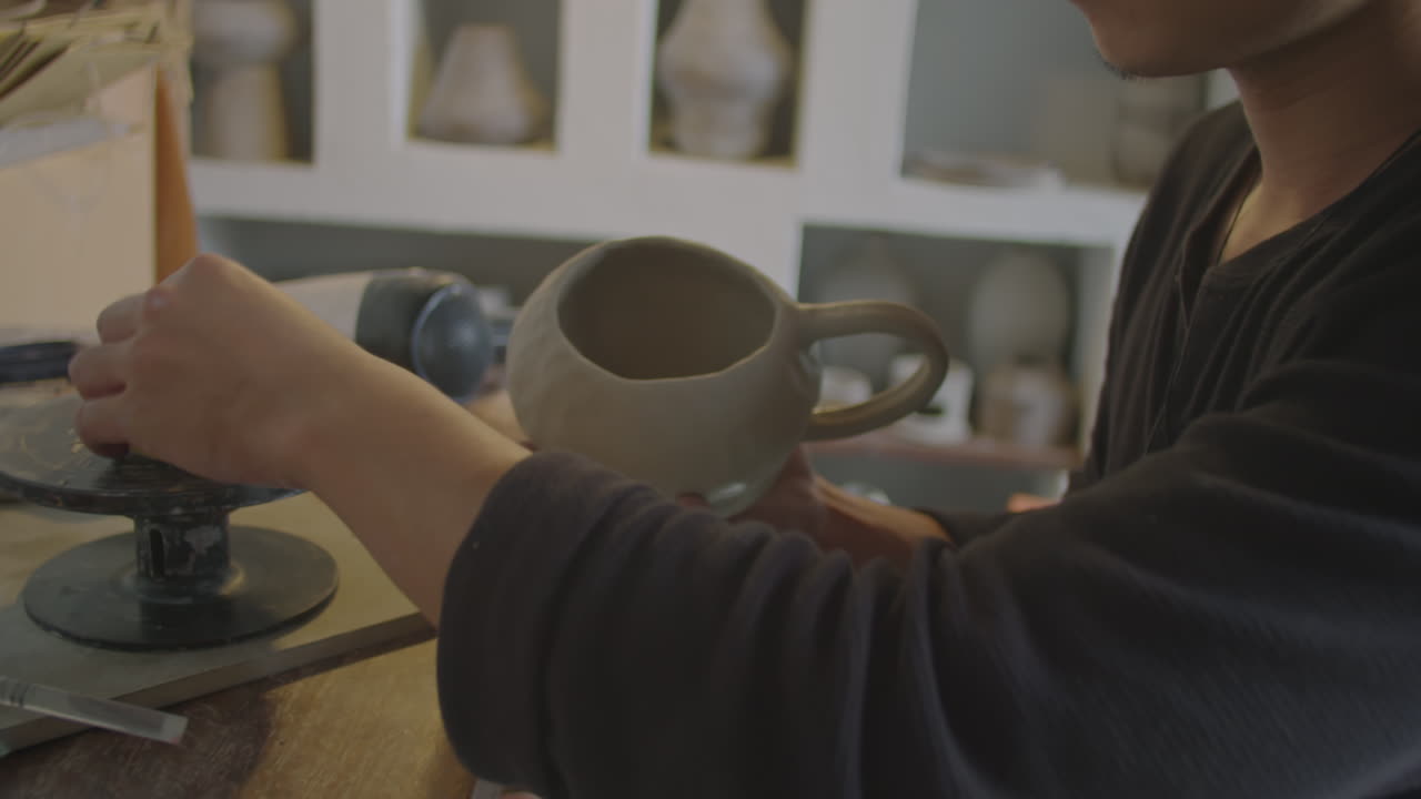 Asian Artisan Working on Ceramic Mug in Pottery Studio