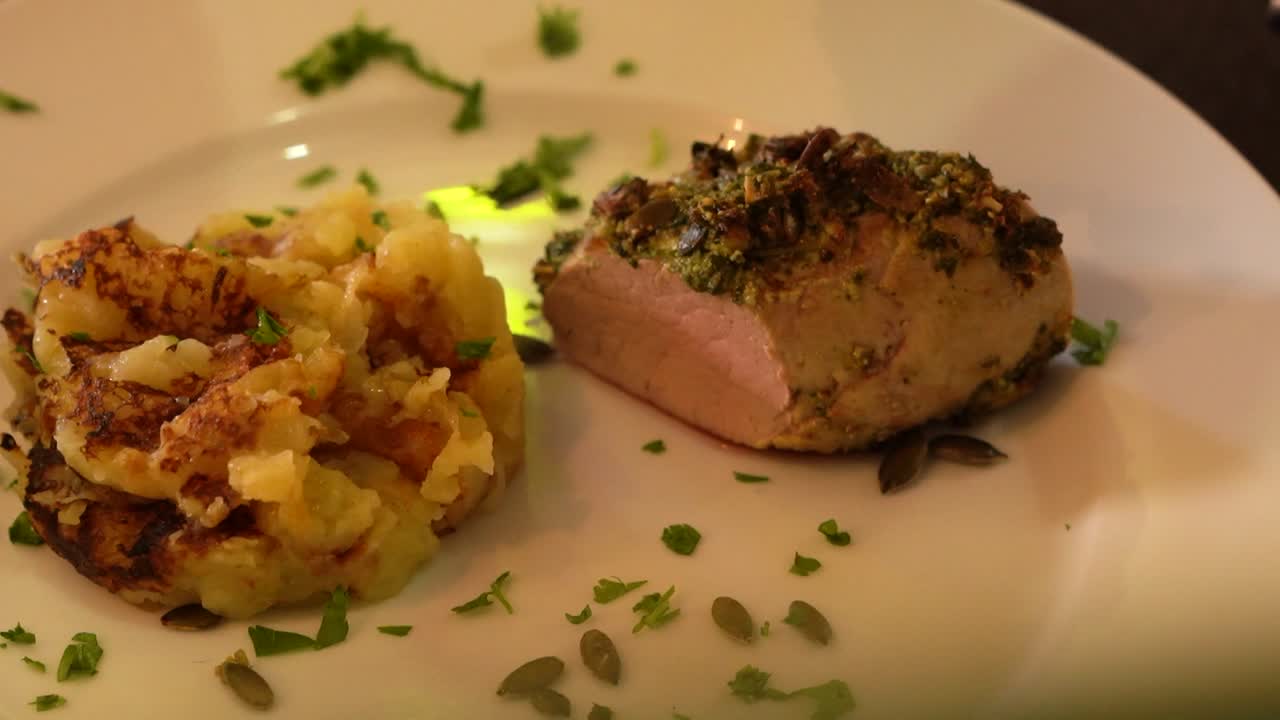 Garnish of seeds, cilantro sprinkled over plate of meat and potatoes before serving.