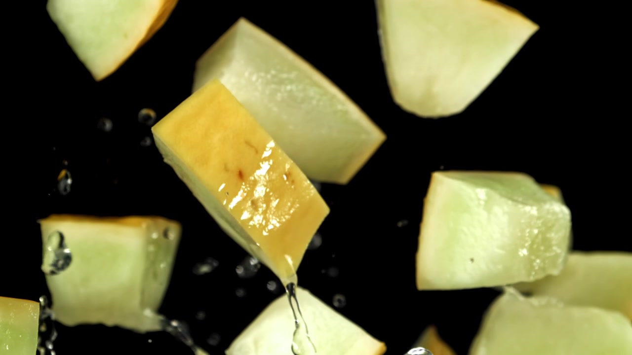 Fresh Melon Chunks Falling and Splashing with Water in Slow Motion