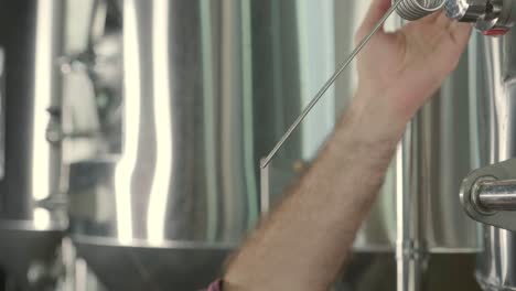 un joven cervecero con un delantal de cuero está probando cerveza en una cervecería moderna