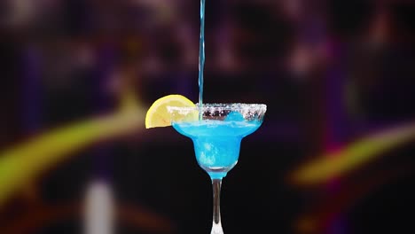 una margarita azul vibrante se vierte en un vaso, adornada con una rebanada de limón, contra un fondo borroso