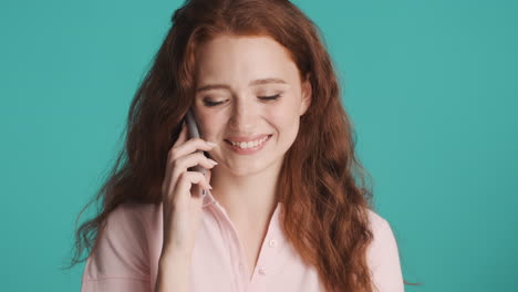 redheaded girl in front of camera on turquoise background.