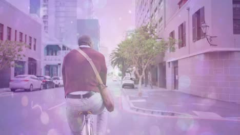 spots of light against rear view of african american man riding a bicycle on the street