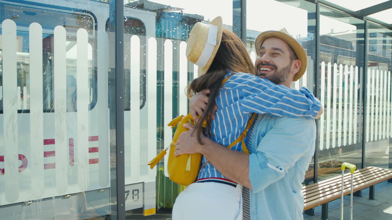 feliz pareja joven caucásica reunida en la estación de tren y abrazándose en un agradable día de verano