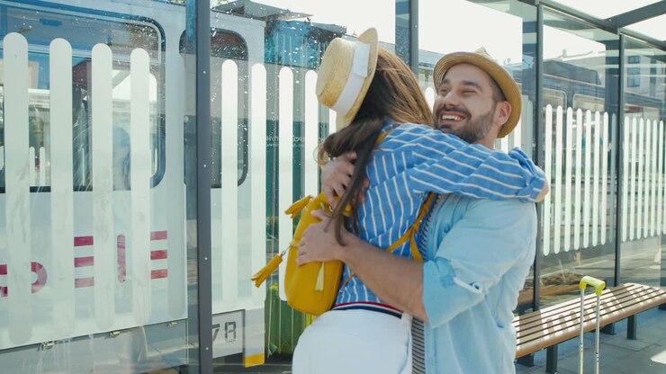 Happy Caucasian young couple meeting at train station and hugging on nice summer day
