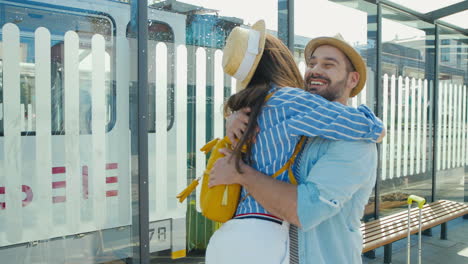 feliz pareja joven caucásica reunida en la estación de tren y abrazándose en un agradable día de verano