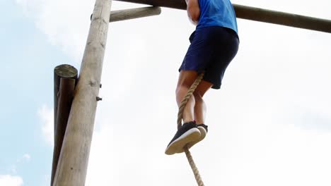 hombre en forma subiendo la cuerda durante el curso de obstáculos 4k