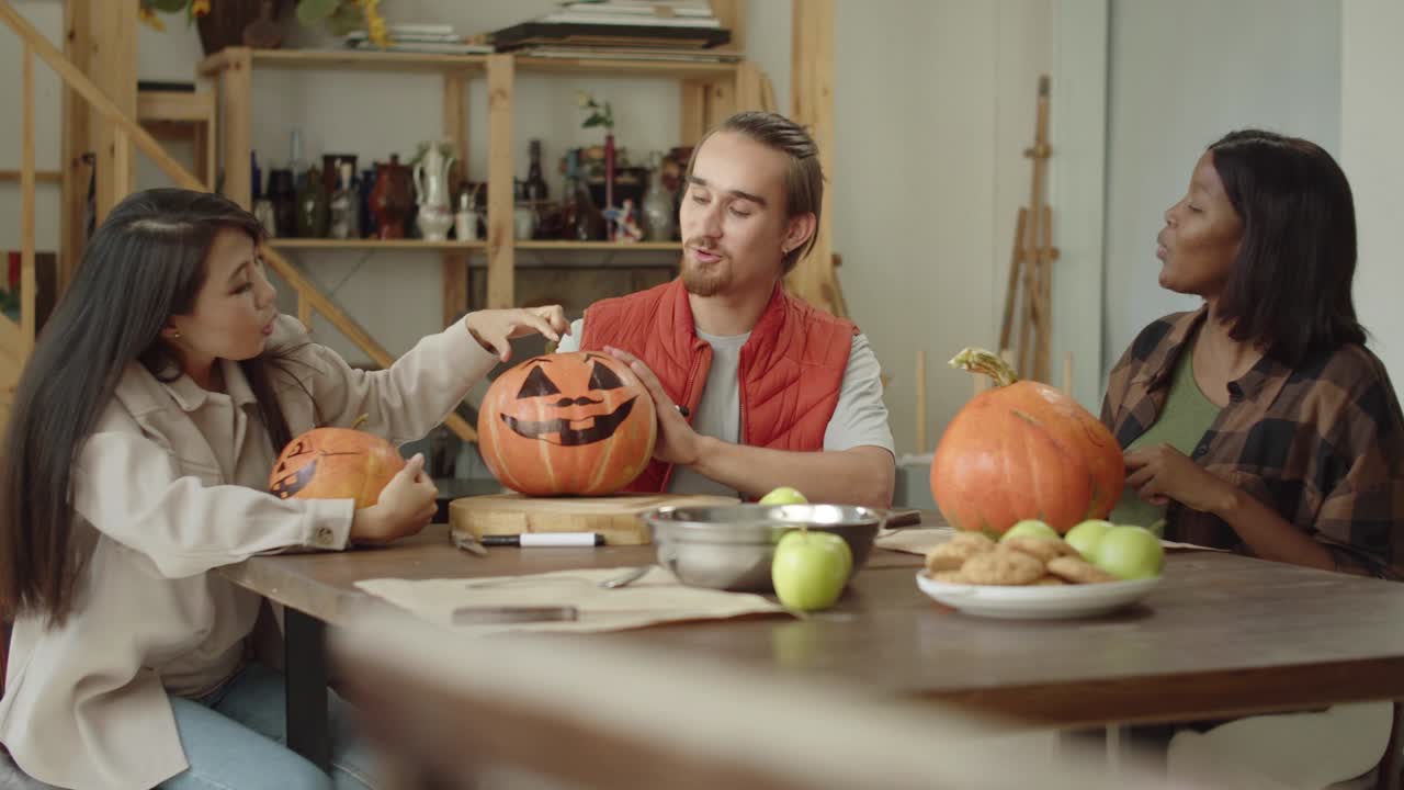 한 남자가 할로윈 호박의 을 채우고 소녀들이 그것을 보고 있습니다.