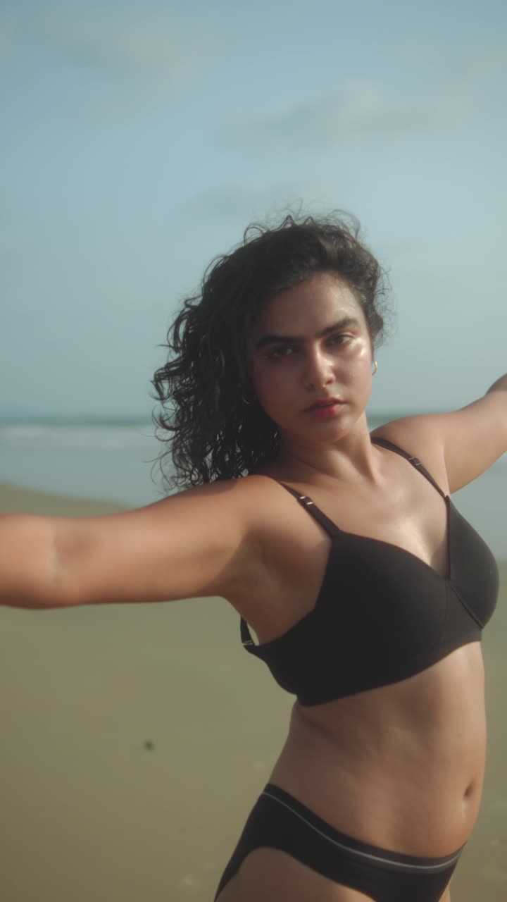 Woman spinning on the beach, hair flowing in the wind with a dreamy, carefree vibe