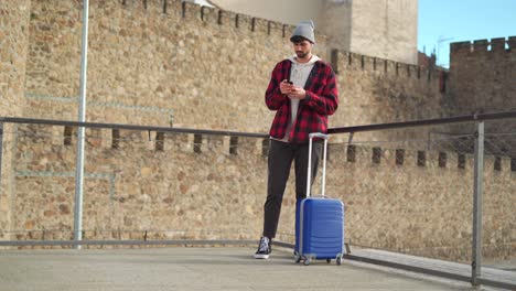 viajero con una maleta enviando un mensaje en el teléfono móvil