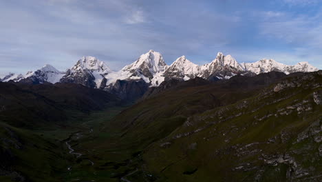 Cinematic aerial view of snowy Andes mountains in Peru with glaciers, rocky cliffs, and hidden blue alpine lake under misty clouds, dramatic landscape and natural travel destination